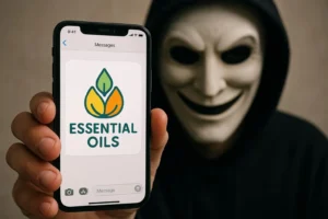 A hand holding a smartphone displaying an "ESSENTIAL OILS" message, with a sinister, masked figure lurking in the background, symbolizing the deceptive and predatory nature of essential oils MLM scams.