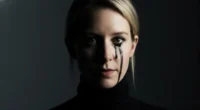 A cinematic close-up of Elizabeth Holmes, portraying the Theranos fraud. Her face is half in shadow, and a single black tear is running from her eye.