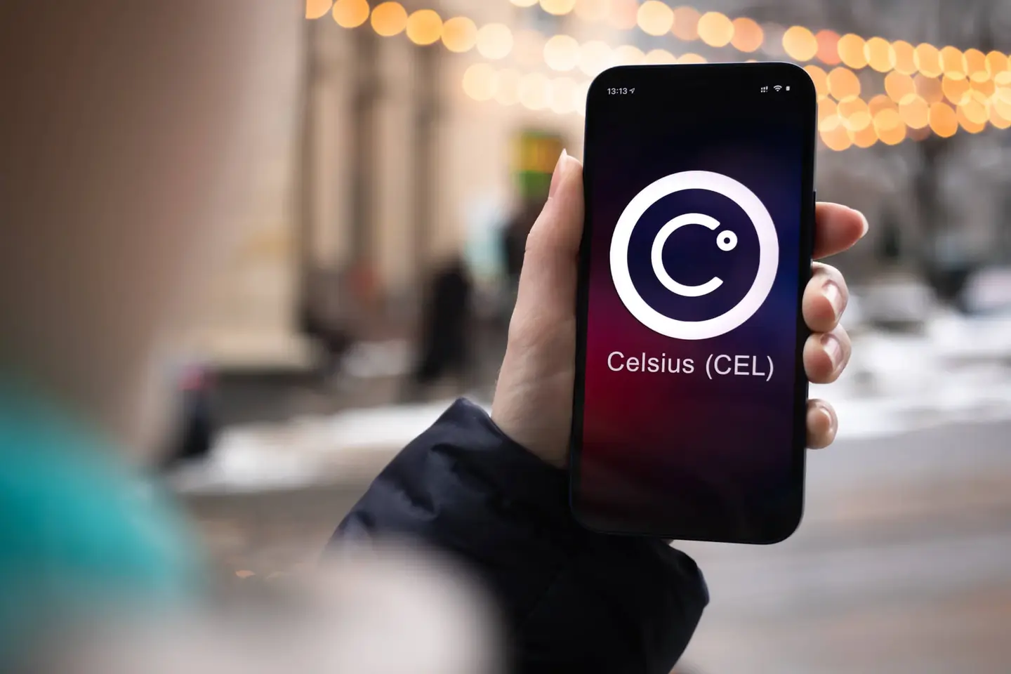 A hand holding a smartphone displaying the Celsius app logo, the platform where 1.7 million users' funds were trapped during the Celsius Network bankruptcy.